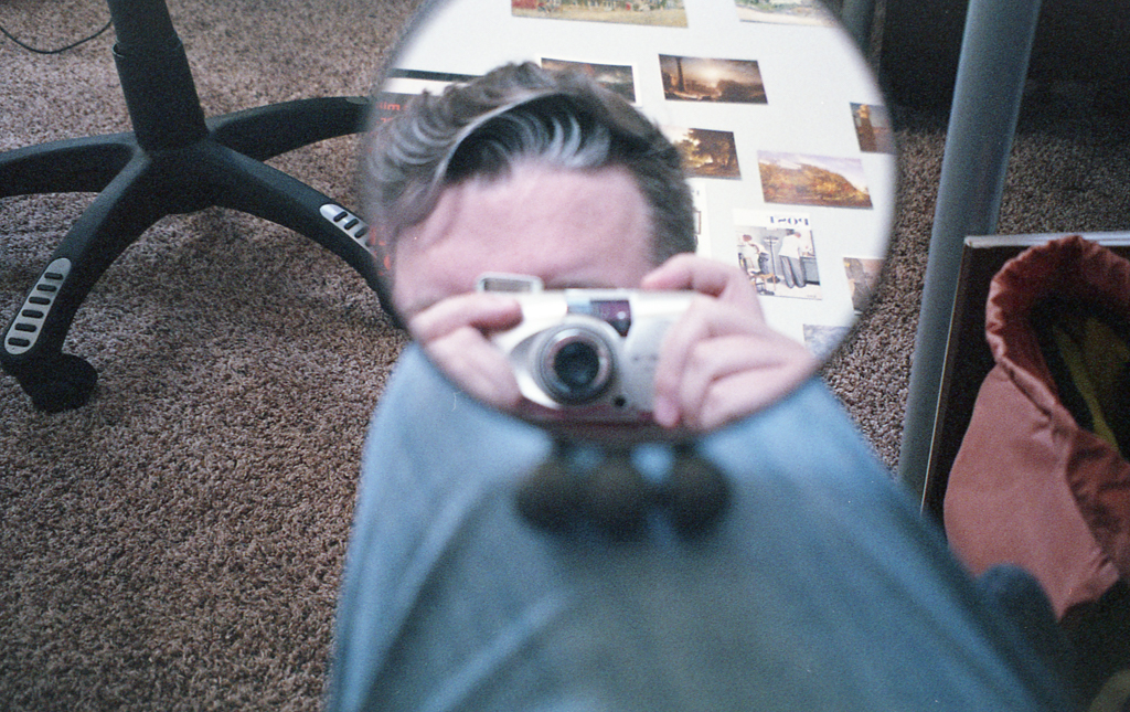 Polatoid of Ponders on a pier with camera, ready to take a picture off the right side of the frame.
