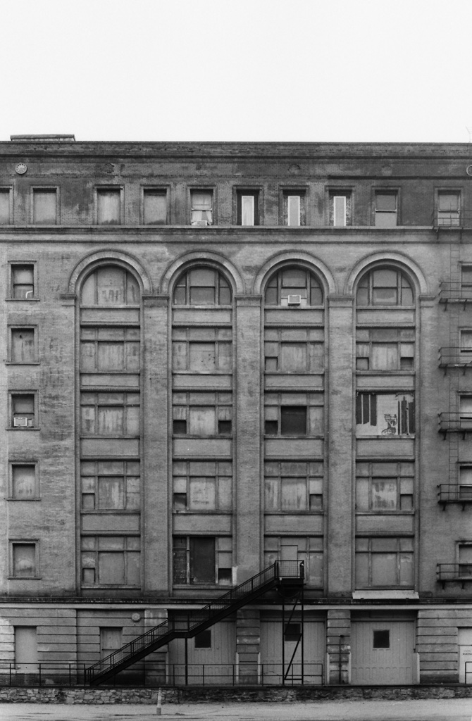 An abandoned seven-story industrial building with boarded-up windows stands in the Soggy Bottoms of Kansas City.