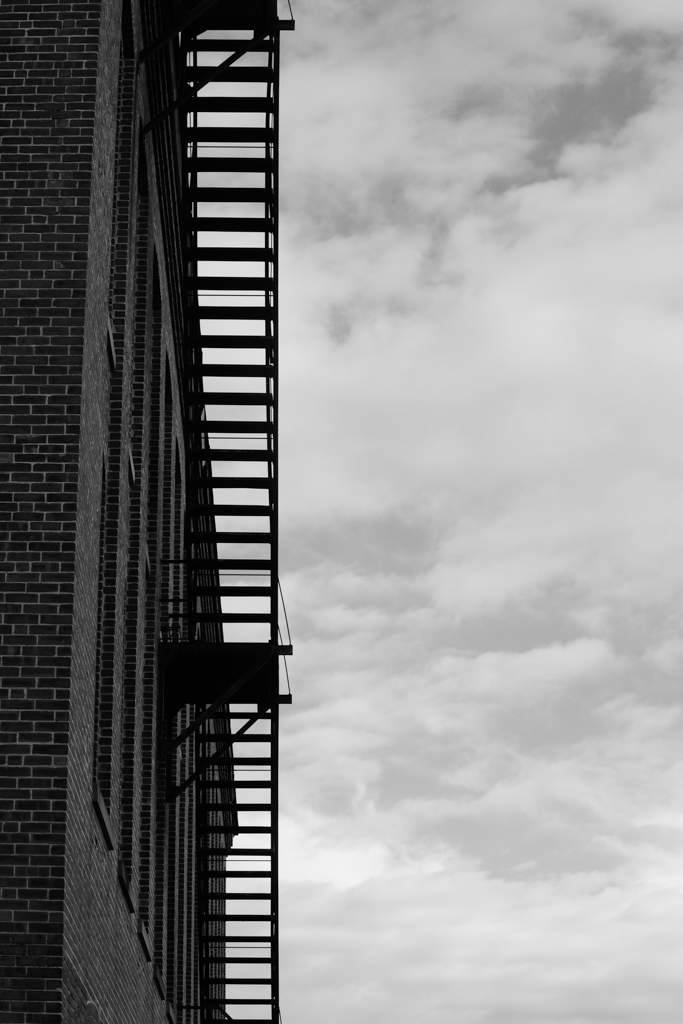 The fire stairs on the side of an industrial building, shot from below.