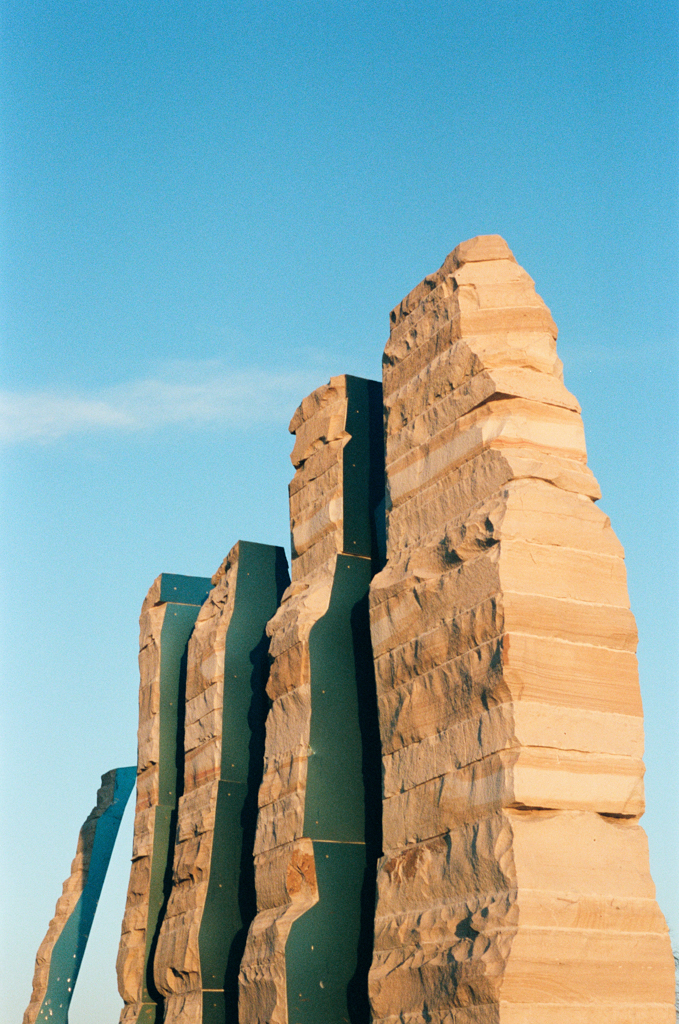A sculpture of sandstone layers representing the foothills of northern Colorado reaches upward into a cerulean blue sky.