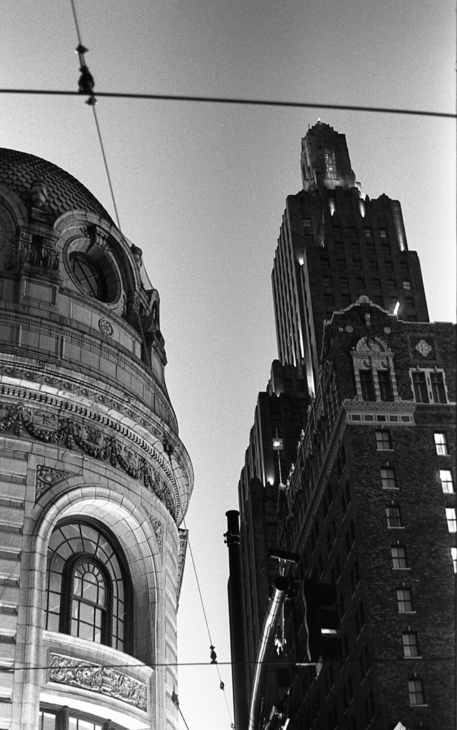 Looking up at two ornate buildings in downtown Kansas City, through telephone wires crisscrossing.